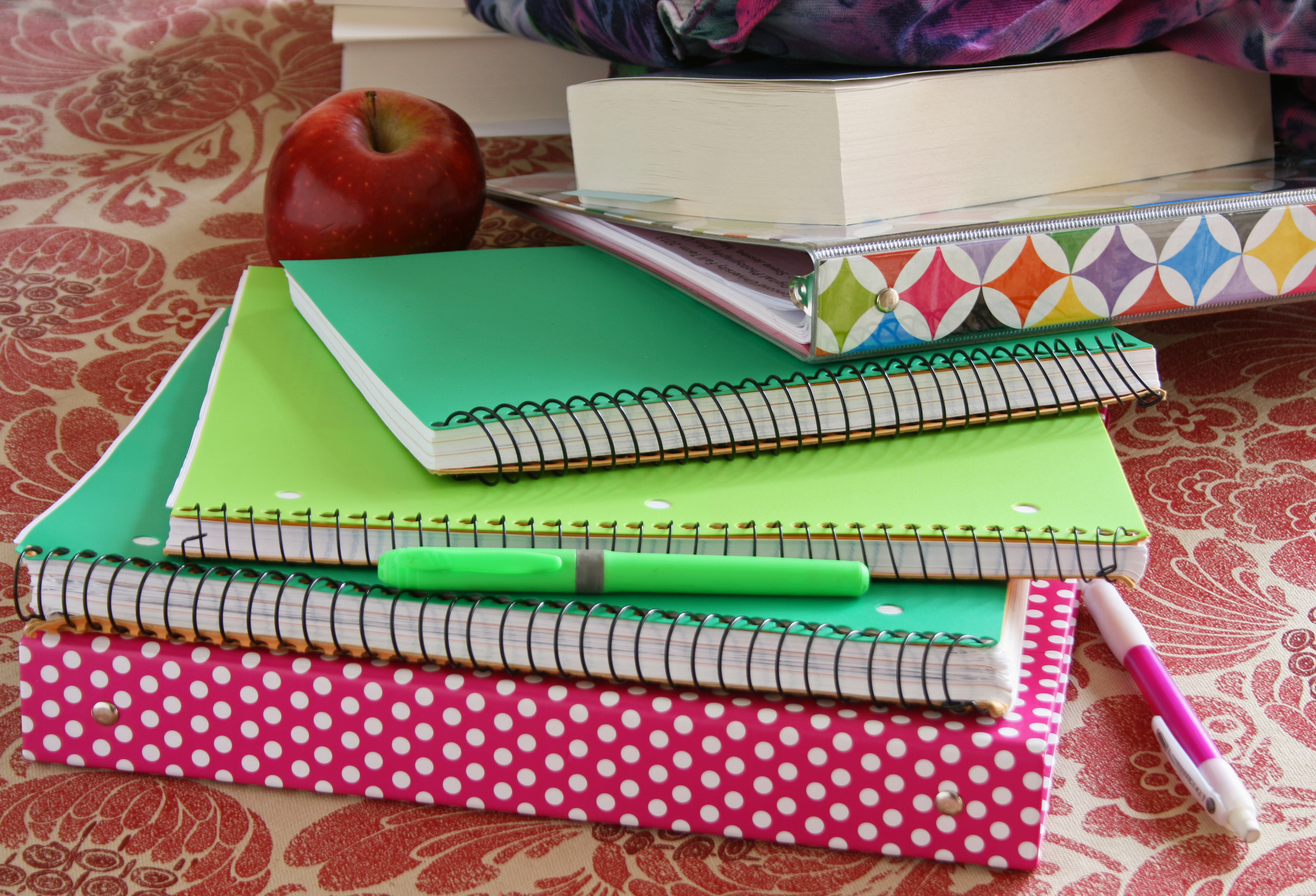 Closeup of school notebooks on a table with an apple